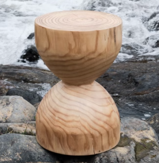 Natural wood stool, hourglass shape, on rocks with water background. Customizable size.