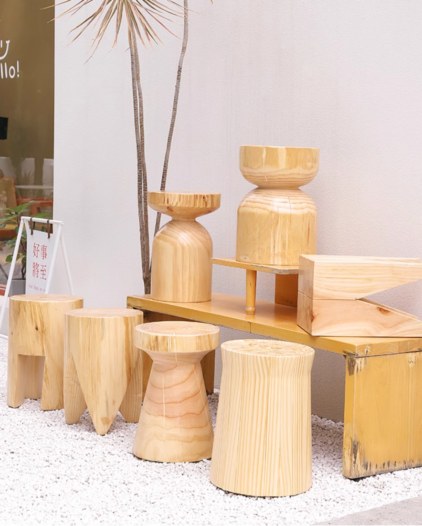 Assortment of natural wood stools, customizable size, displayed on white gravel.