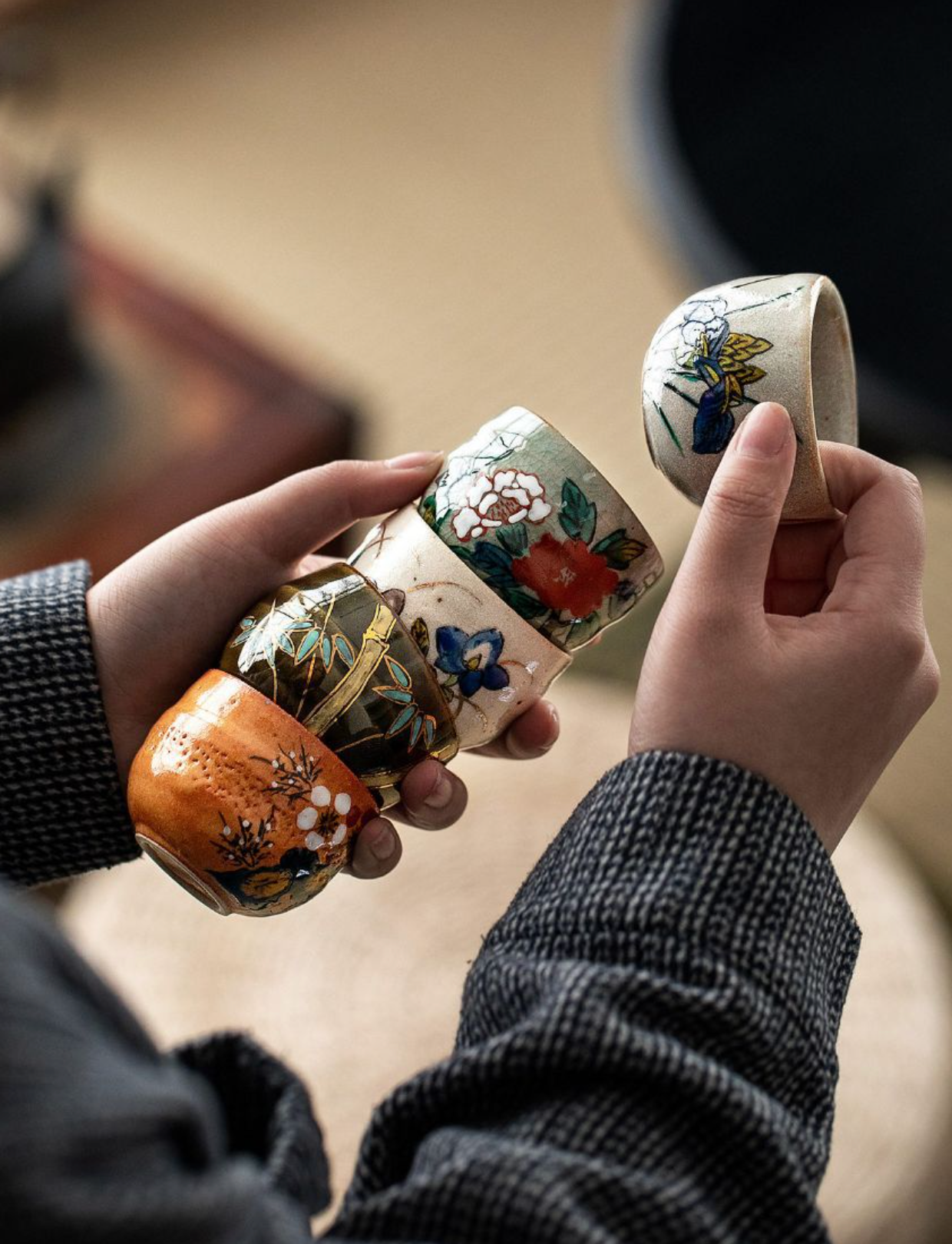 Five-Herb Flower Tea Cup Set: colorful ceramic cups with floral designs, held by hands.