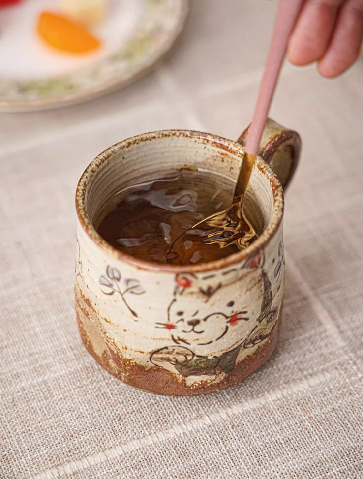 Hand painted coffee mug, 11oz, with cute cat design, on textured linen tablecloth.