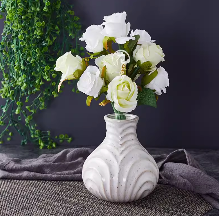 White ceramic small vase with white roses on dark background