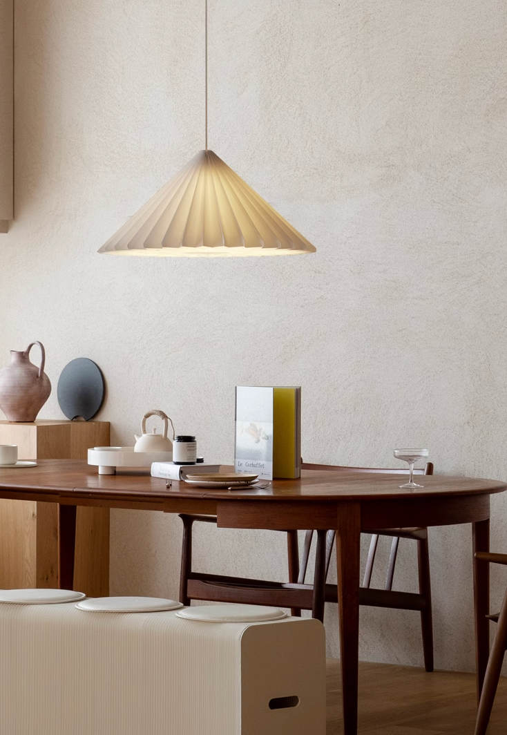 Geometric origami paper lampshade in off-white, casting warm light in a modern dining setting.