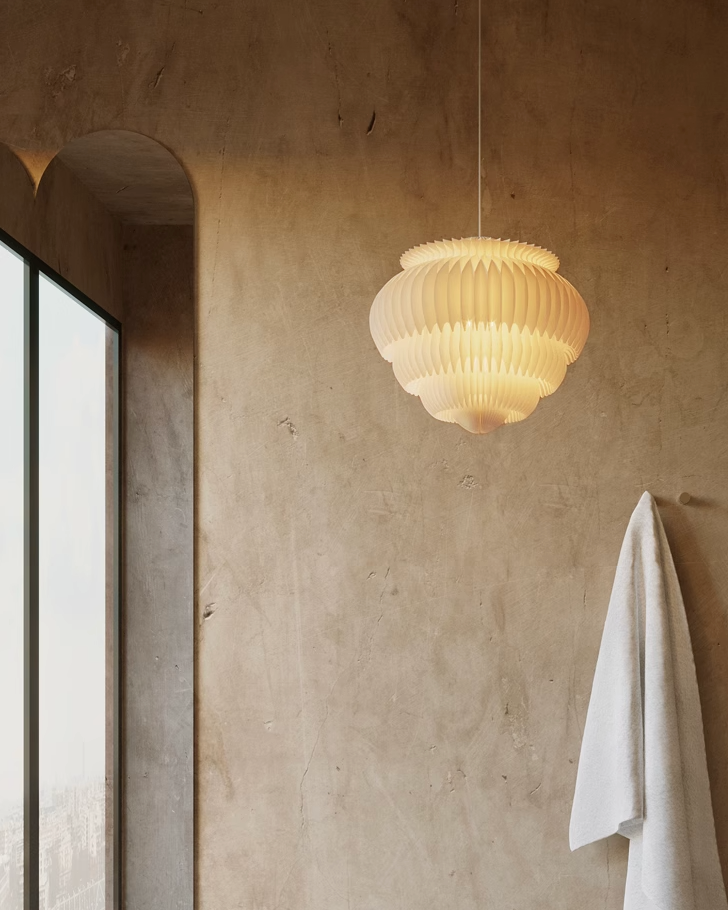 White geometric origami paper lampshade hanging in a modern room with textured walls.