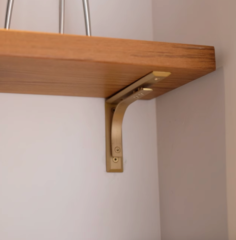 Warm gold curved minimalist pattern unlacquered brass shelf brackets with a smooth brushed finish for modern wall shelving.