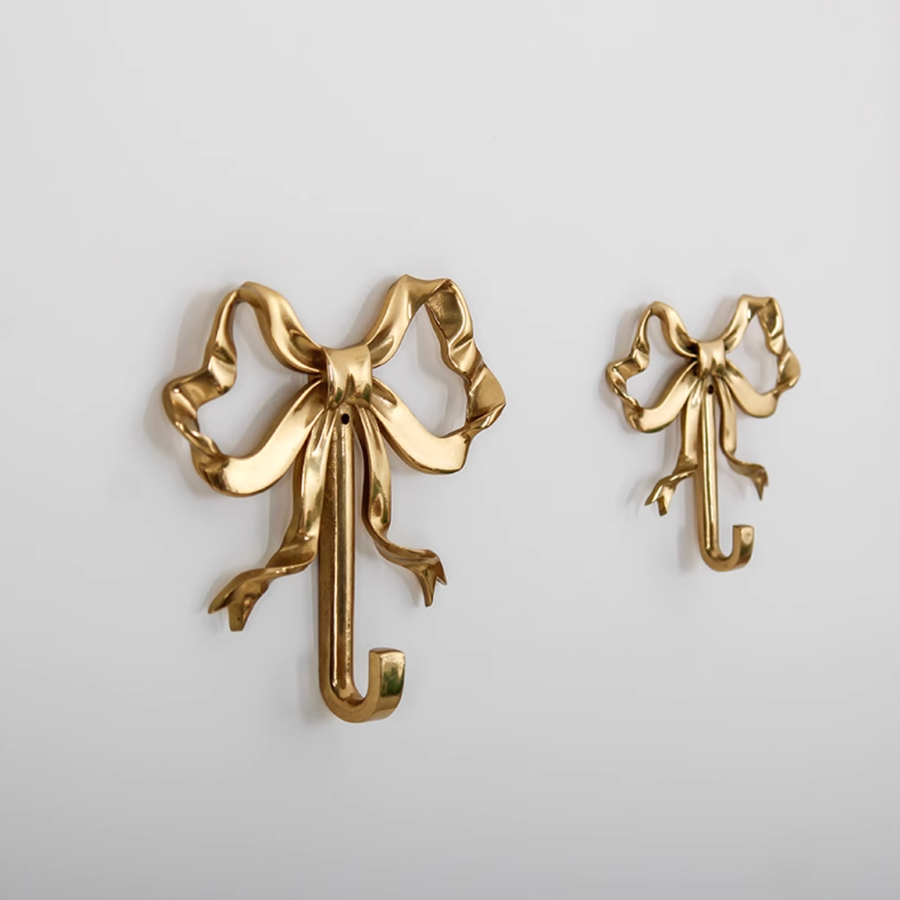Two polished brass bow wall hooks, decorative home decor accents.