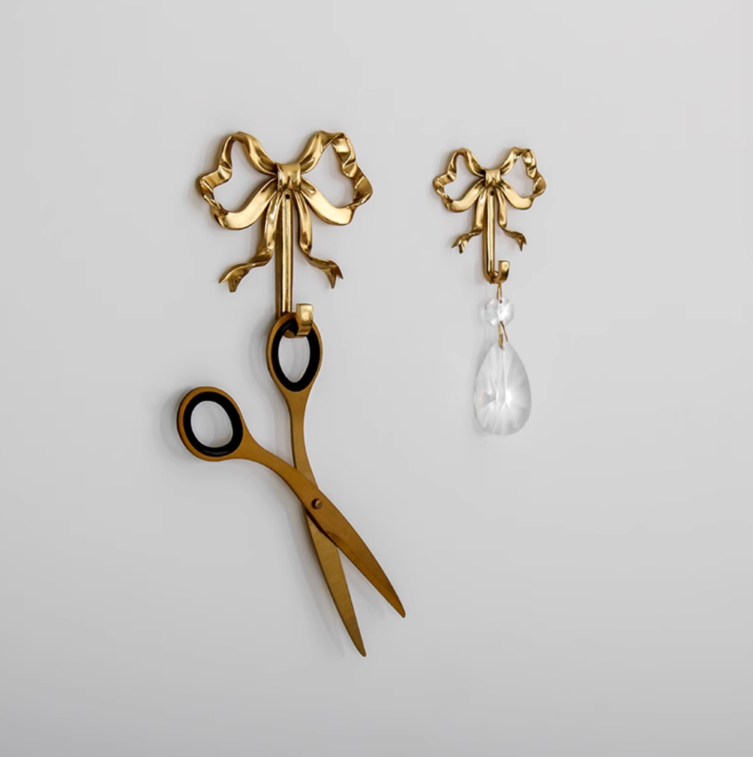 Brass Tie Wall Hook with ornate bow design, holding decorative scissors and crystal.