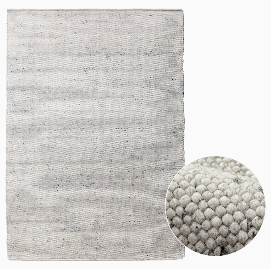 Light grey natural wool carpet with a textured weave, showcasing a close-up of its soft, loop pile.