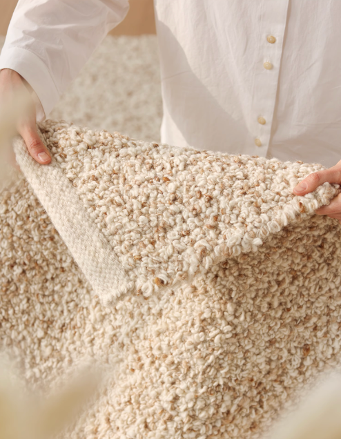 Hand-woven wool shaggy rug in neutral cream and tan boucle texture, home decor.