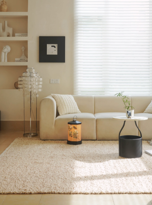 Cream hand-woven wool shaggy rug under a beige sofa in a bright living room.