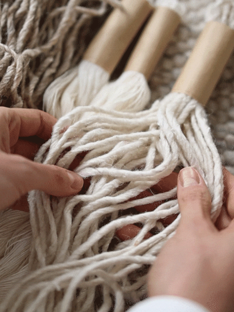 Hands weaving a cream hand-woven wool shaggy rug with natural rope details.