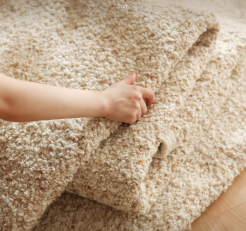 Soft, hand-woven wool shaggy rug in a natural, creamy beige color, showing texture.