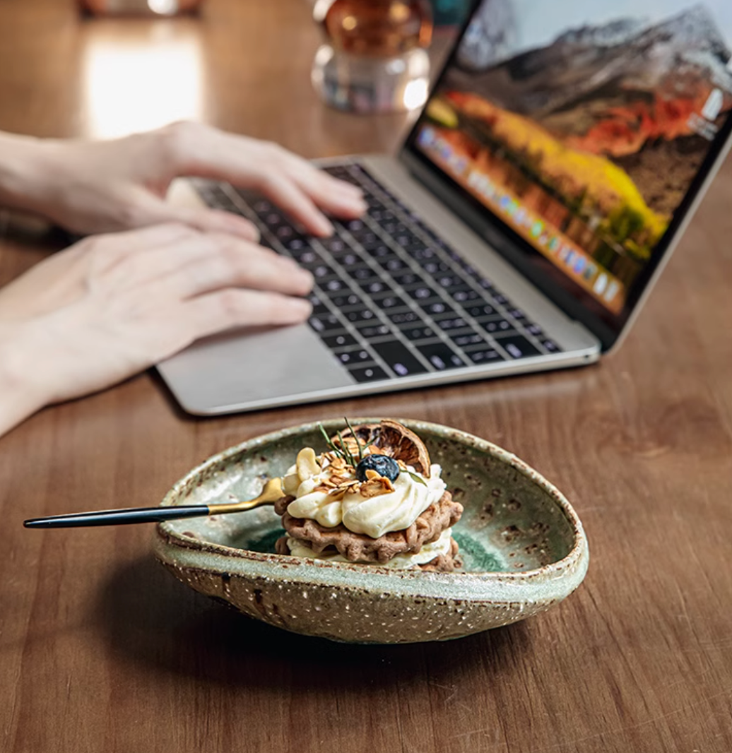 Green ceramic bowl with dessert, artisanal design.