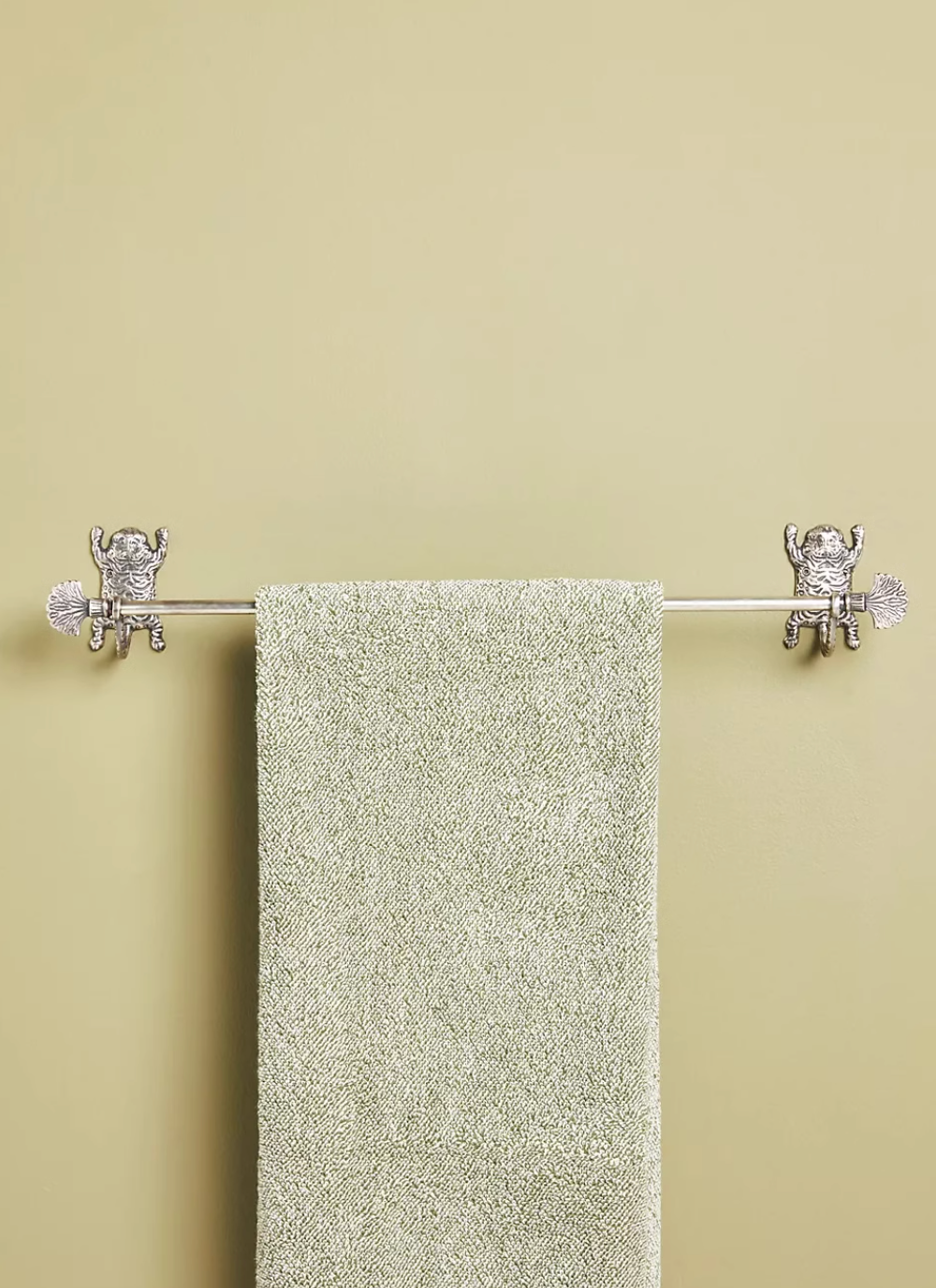 Silver tiger-inspired bathroom accessories set holding a textured green towel.