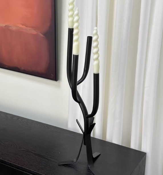 Modern Branch Candle Holder in black metal with cream spiral candles on dark wood surface.
