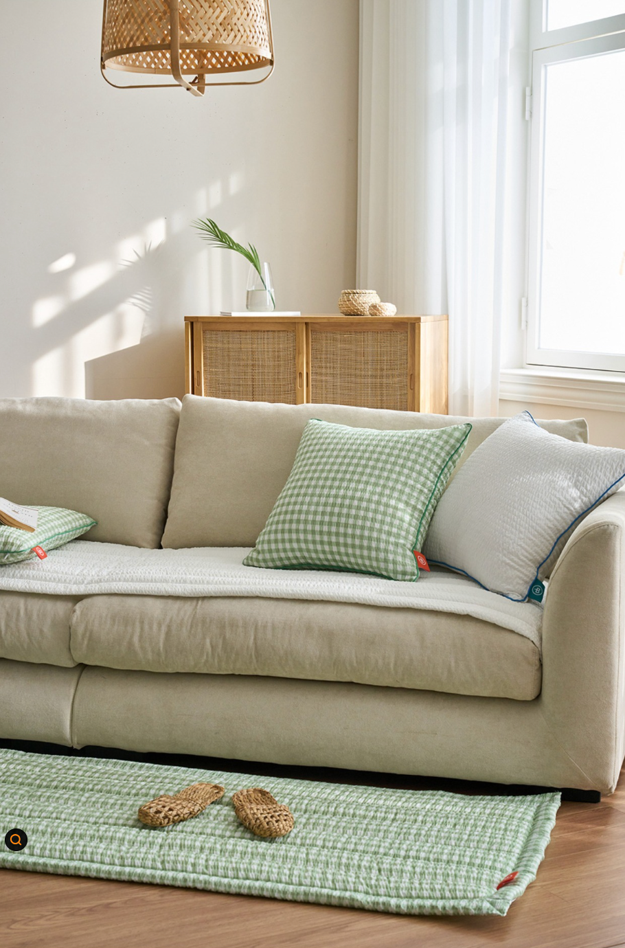 Green Gingham Sofa Protector & Rug Set on neutral sofa, with woven rug and slippers. Cozy decor.