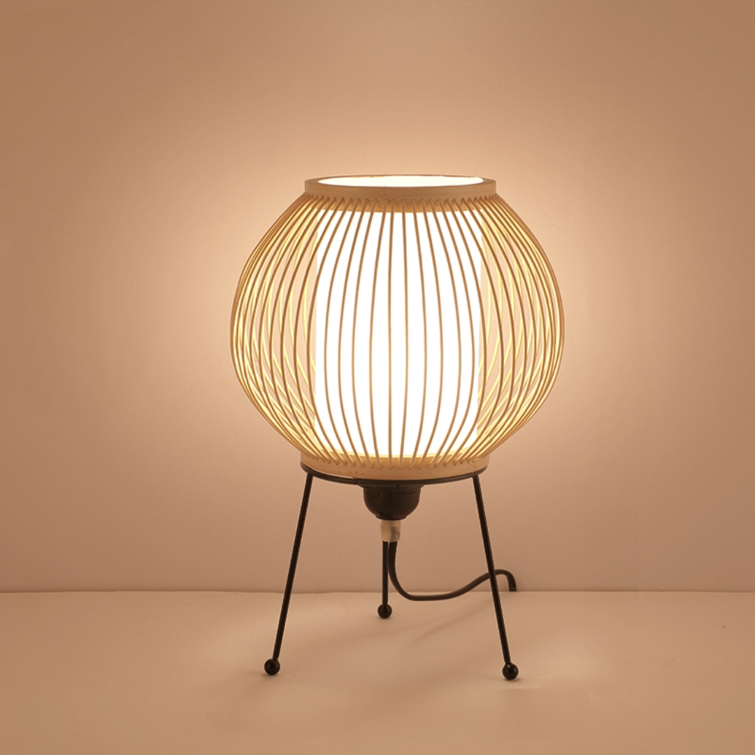 Woven natural rattan table lamp with a modern tripod base, emitting a warm glow.