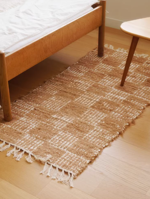 Handwoven cotton checkered rug 2.3x4.6 in natural brown and white, on wooden floor.