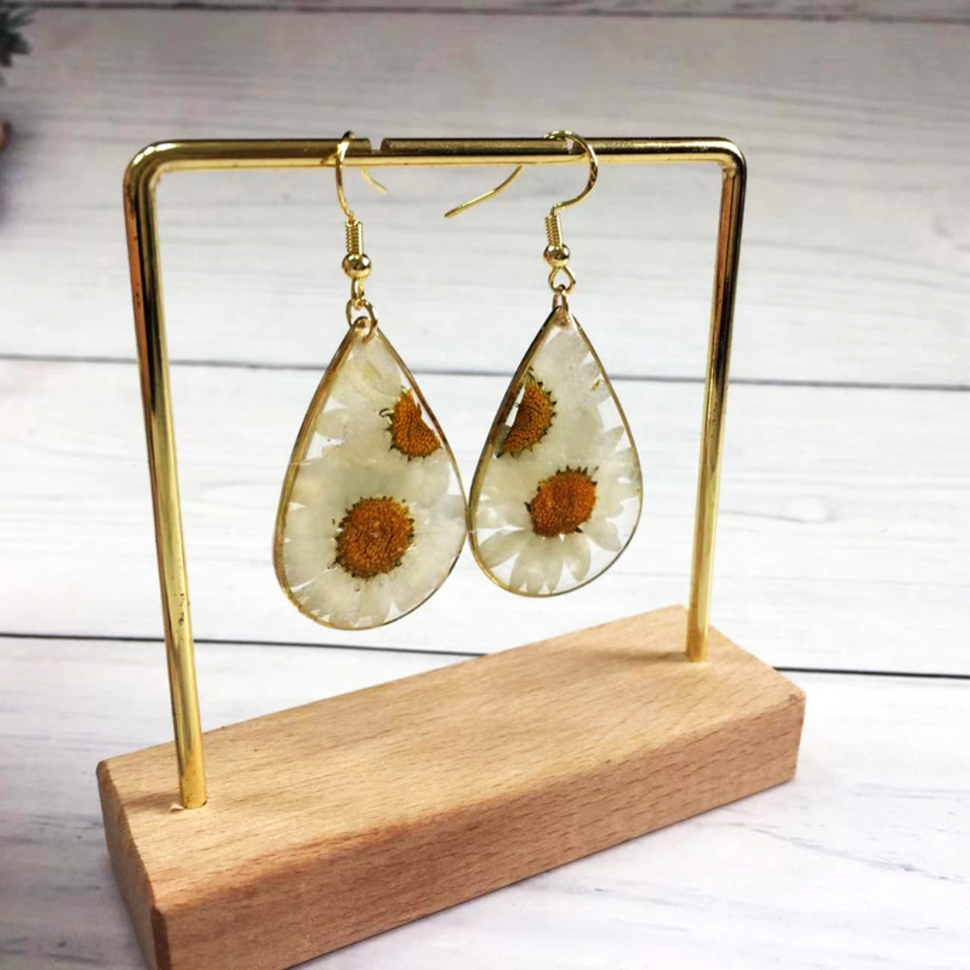 Pressed flower earrings with gold plated accents featuring white daisies in clear resin.