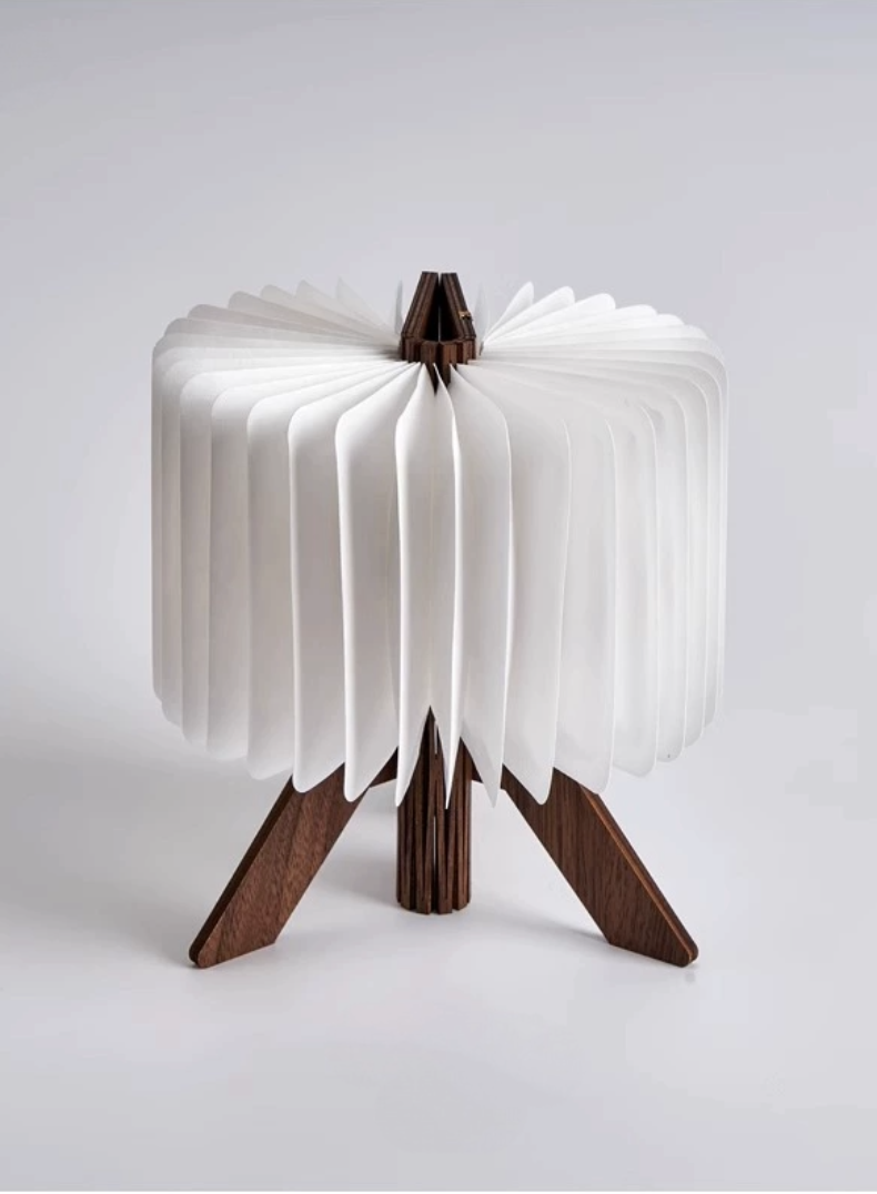White folding portable paper lamp with dark wood base on a light background.