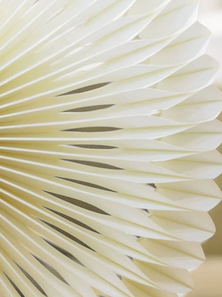 Cream paper bedside lamp with intricate origami folds, bell-shaped design