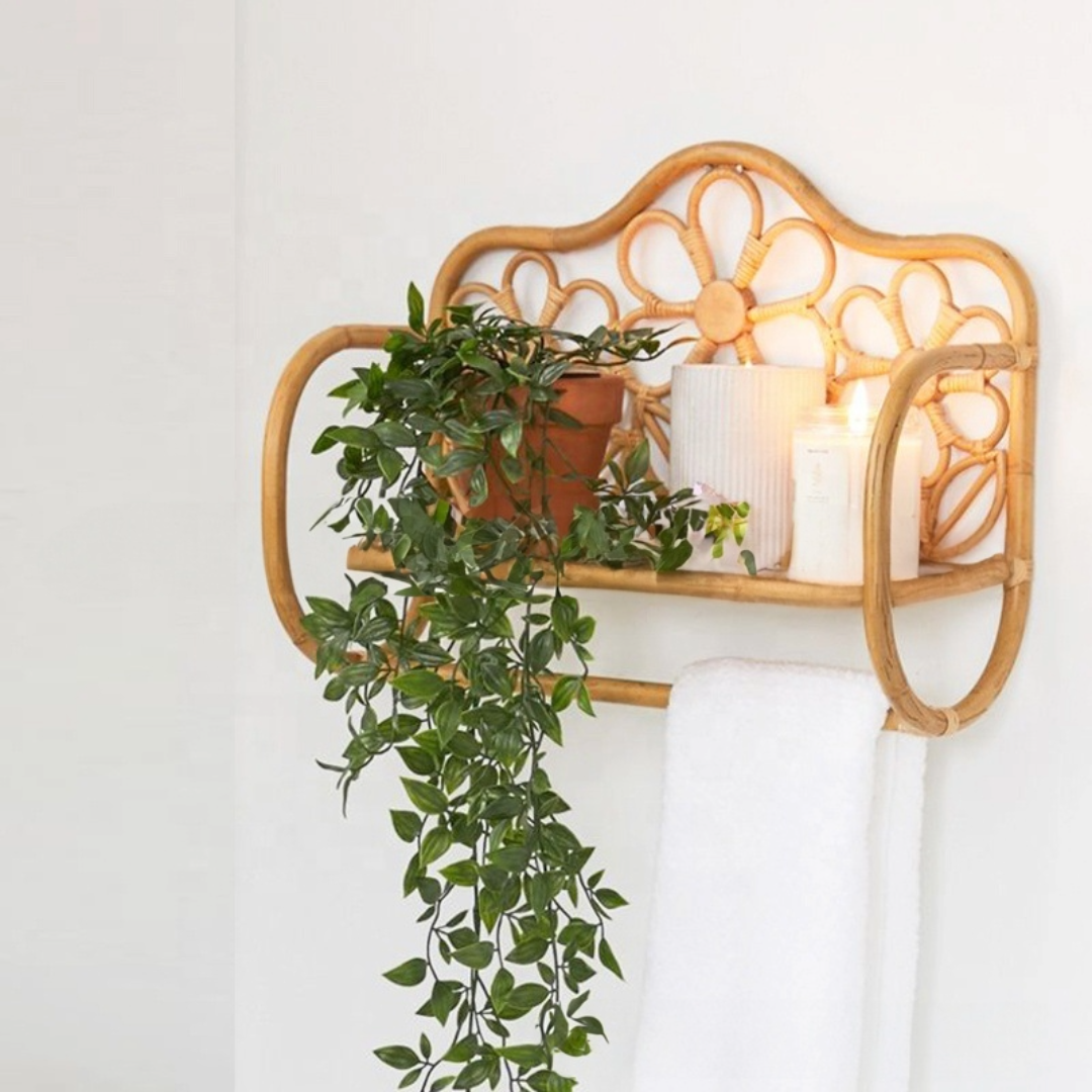 Rattan wall shelf with flower pattern, holding plants and candles. White towel hangs below.