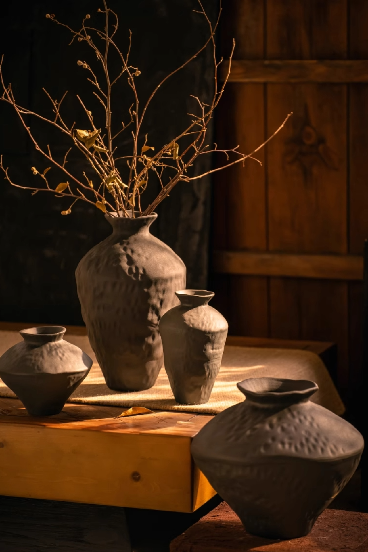 Ceramic black irregular flower vase, part of a rustic home decor display with dried branches.