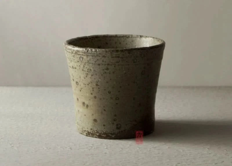 Handmade stoneware brown dinnerware set, speckled ceramic tumbler on a light surface.