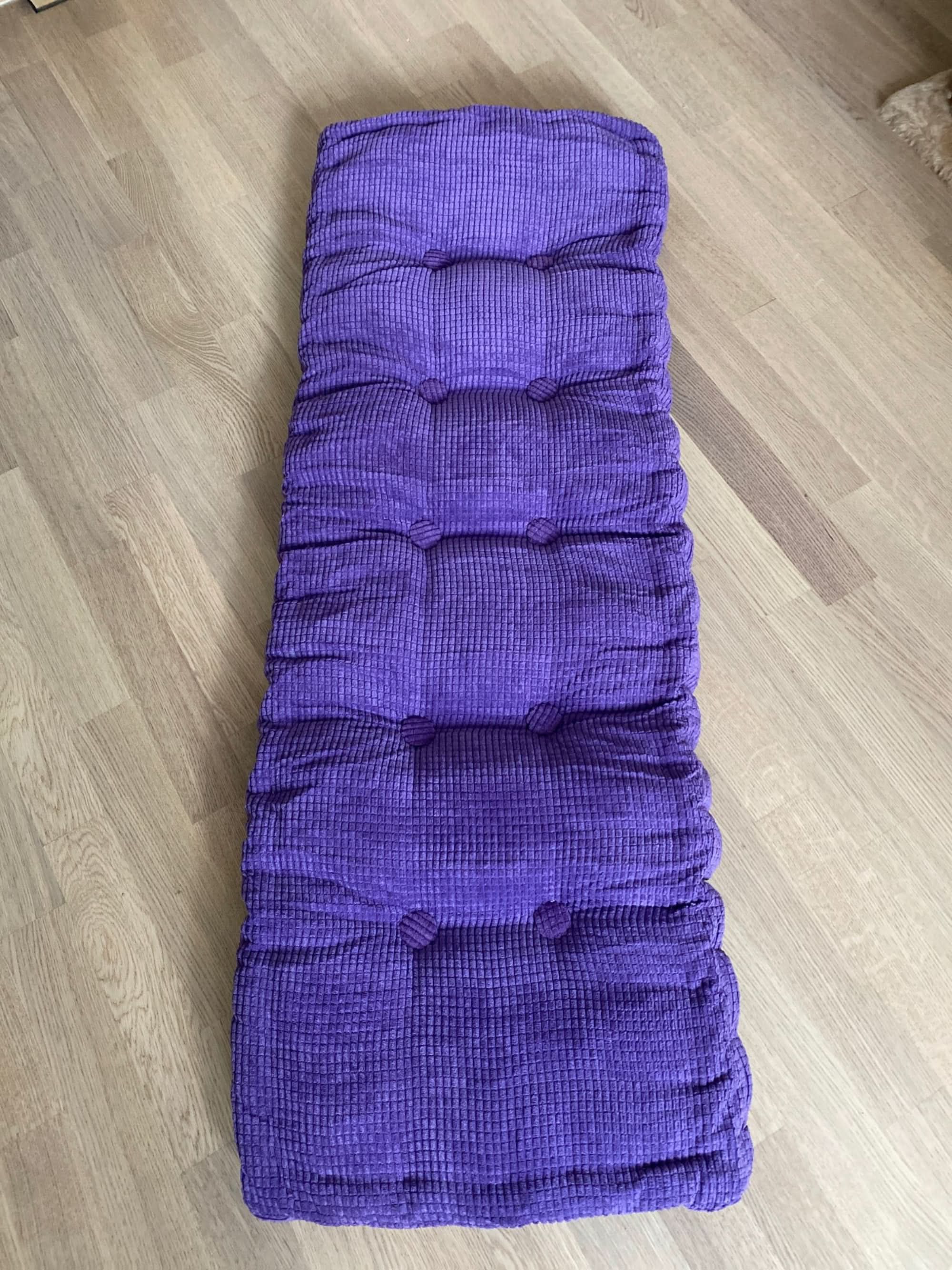 Plush purple tufted custom window seat cushion on wood floor