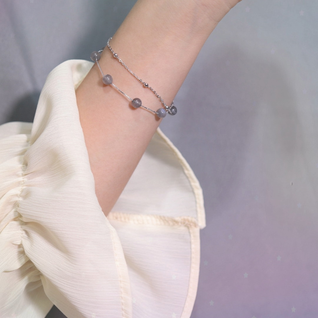 Delicate S925 silver moonstone bracelet with grey beaded accents on a woman's wrist.
