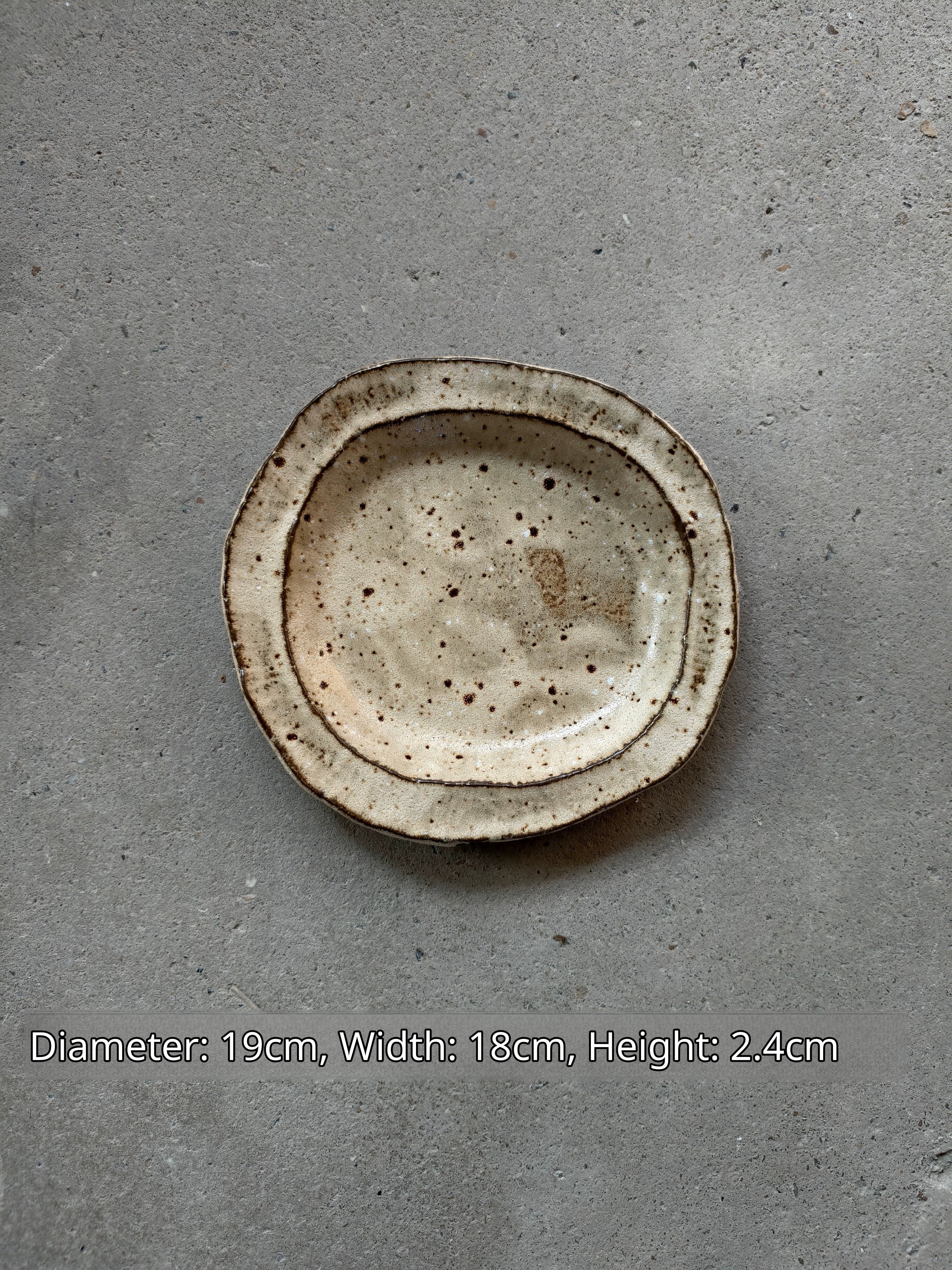 Oval ceramic plate in speckled beige and brown, 19x18x2.4cm, viewed from top, similar to Image 1.