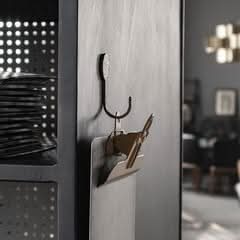 Hammered brass wall hook holding keys on a dark metallic surface, home decor.