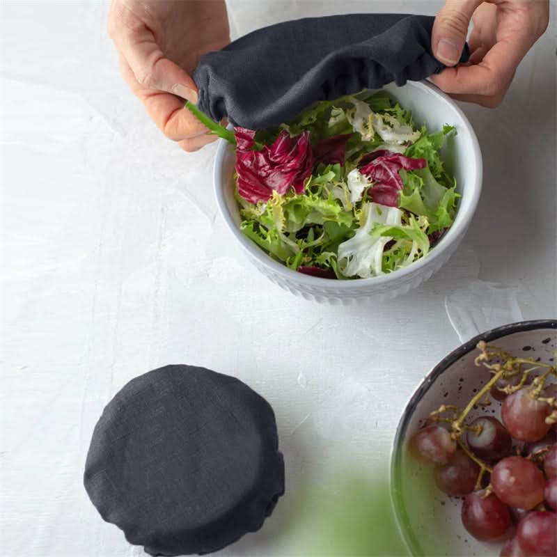Dark grey linen bowl covers shown in use over a salad bowl. Home decor.