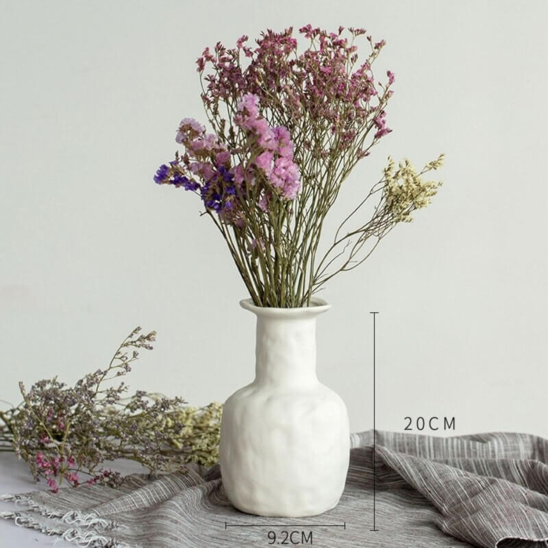 Abstract white ceramic vase with dried flowers, minimalist decor.