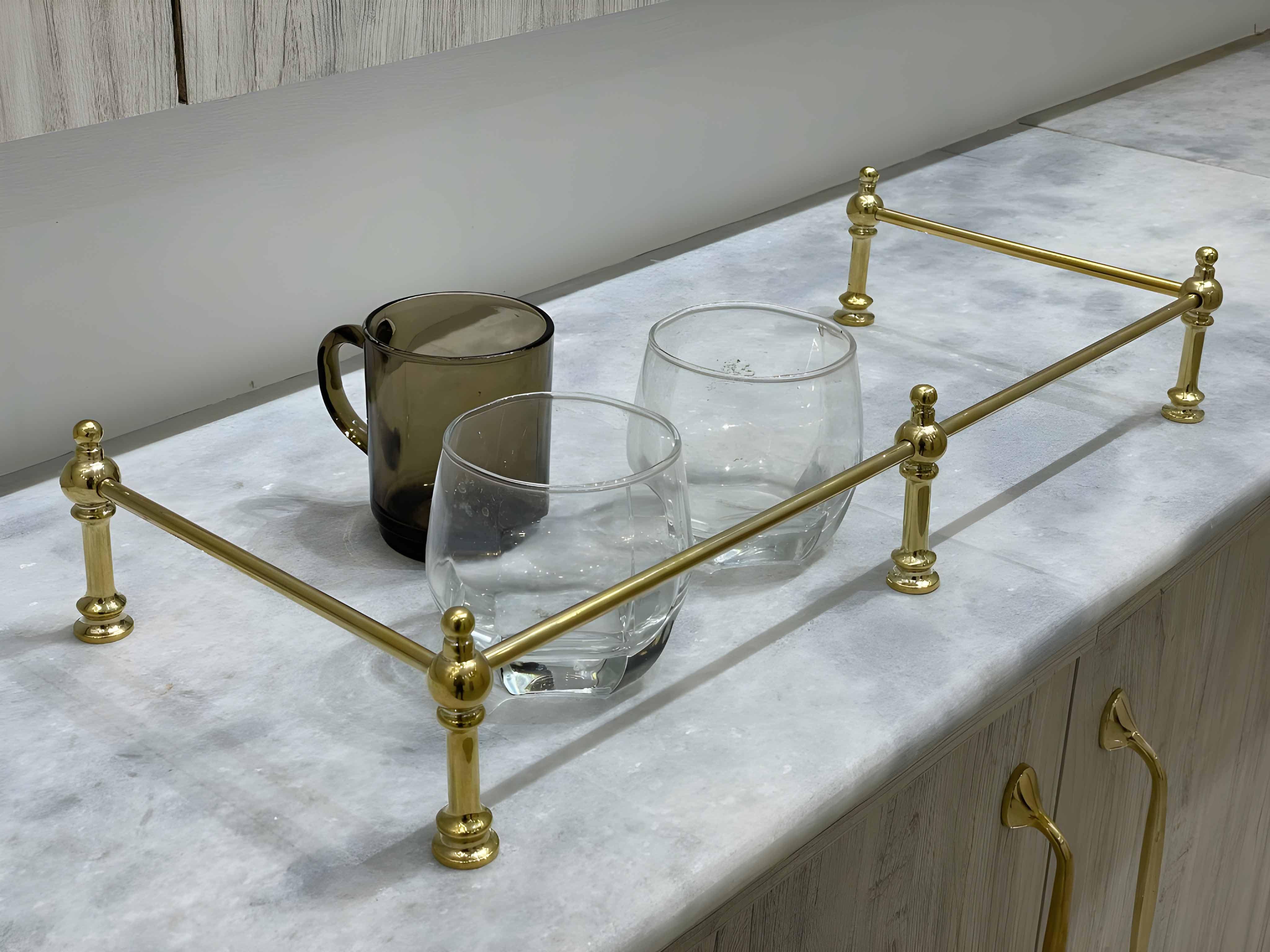 Victorian Brass Gallery Rail with polished brass accents holding two glasses on a marble countertop.
