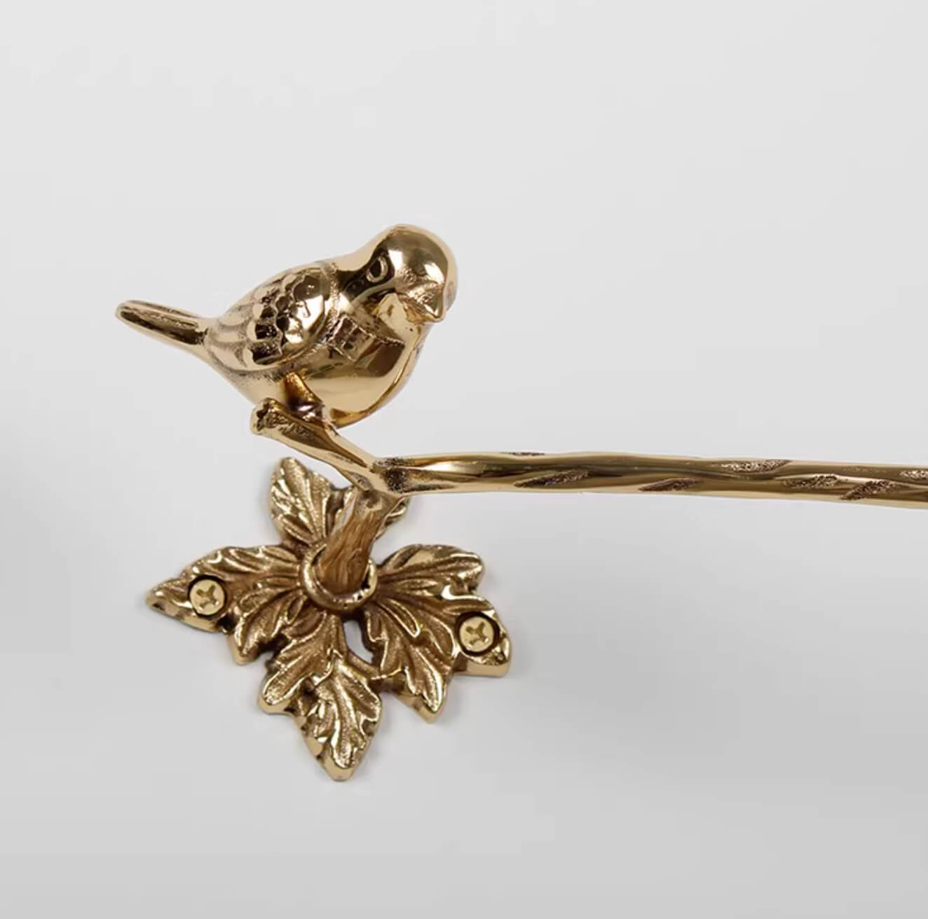 Golden brass bird toilet paper holder with leaf accent, part of the Brass Bird Bathroom Set.