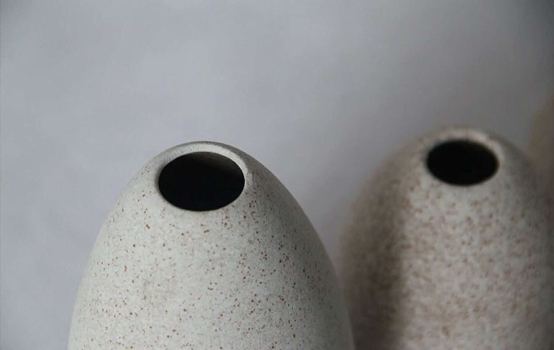 Cream ceramic vase, minimalist design, speckled texture.