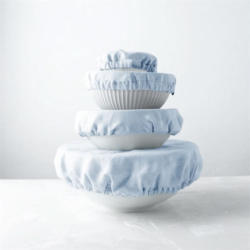 Stack of light blue linen bowl covers on white ceramic bowls against a white background.