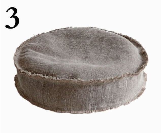Round grey cotton distressed meditation pillow with frayed edges.