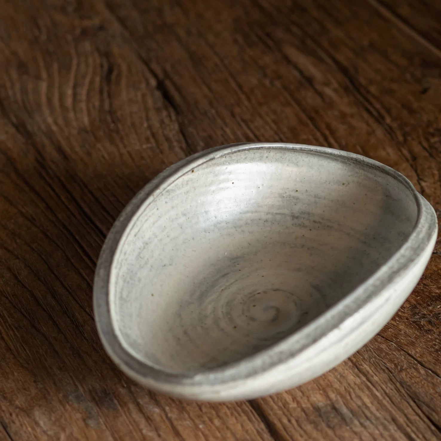Top-down view of an organically shaped, shallow ceramic bowl with a swirling glaze pattern.