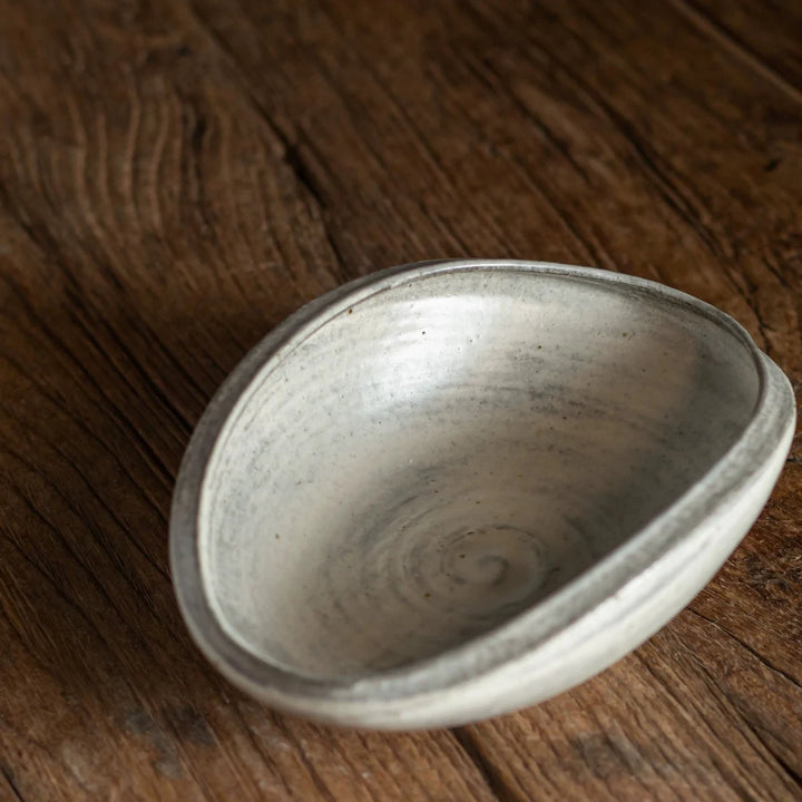 Top-down view of an organically shaped, shallow ceramic bowl with a swirling glaze pattern.