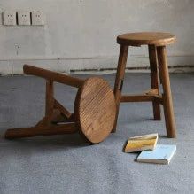 Two rustic wooden stools, natural finish, round tops, simple legs,  on light-colored floor.