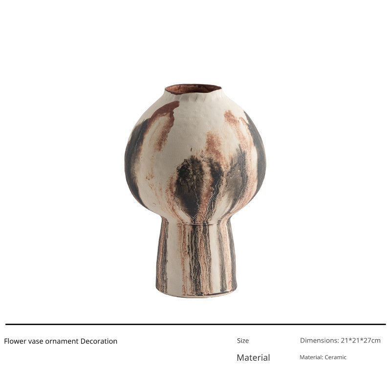 A tall, bulbous ceramic vase with a narrow neck and base, featuring a mottled glaze in earthy tones of white, brown, and black.