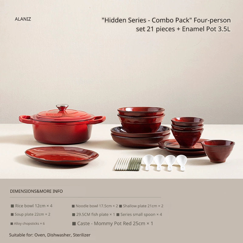 A red enameled Dutch oven with a lid sits on a table next to stacked red bowls, plates, and small spoons.