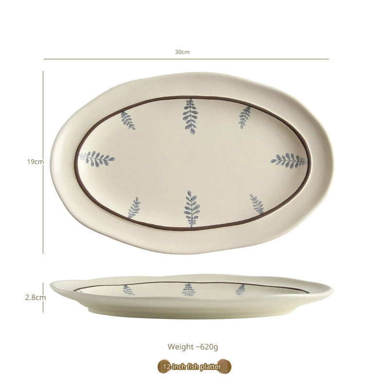 An oval-shaped ceramic serving platter with a hand-painted leaf design and a brown rim.