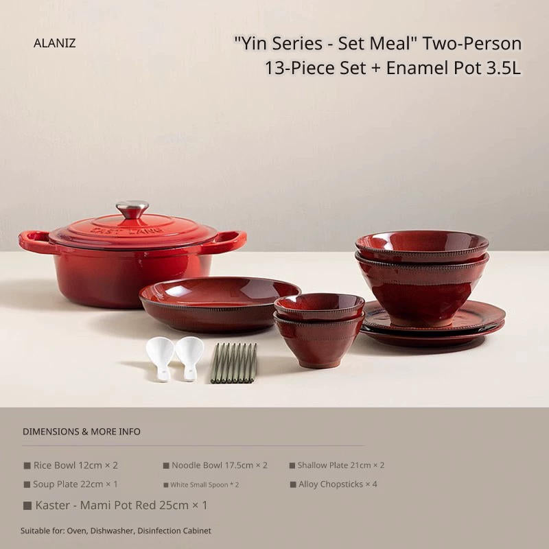 A red cast iron pot and a set of matching red ceramic bowls, plates, and utensils are displayed on a white surface.