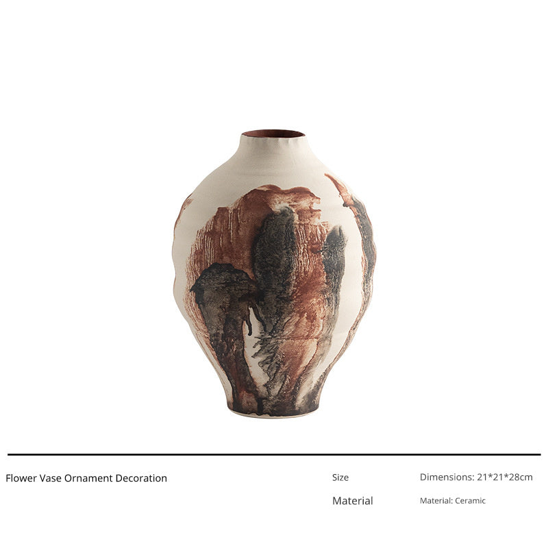 A tall, irregularly shaped ceramic vase with a rustic, abstract design featuring earthy tones of brown and black.