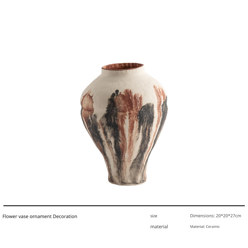A tall, light-colored ceramic vase with a bulbous body and a narrow neck, featuring a dripping glaze effect in shades of brown, black, and rust.