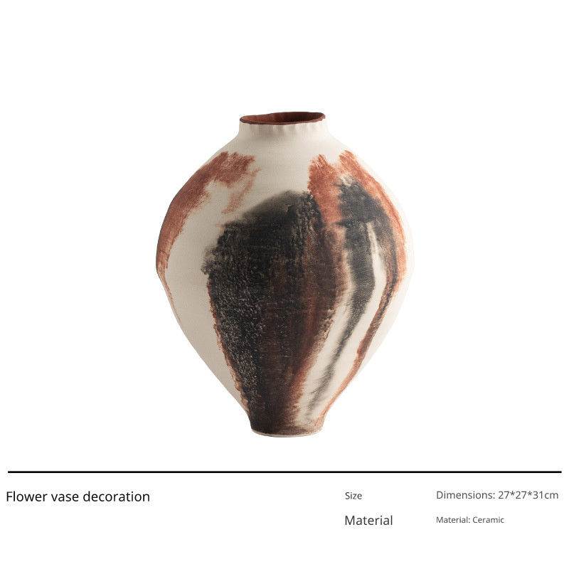 A cream-colored ceramic vase with abstract brown and black brushstrokes is shown against a white background.