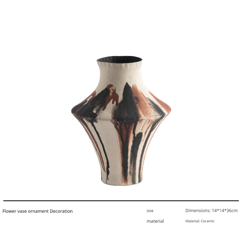 A ceramic vase with a unique, abstract drip glaze design in black, brown, and white.