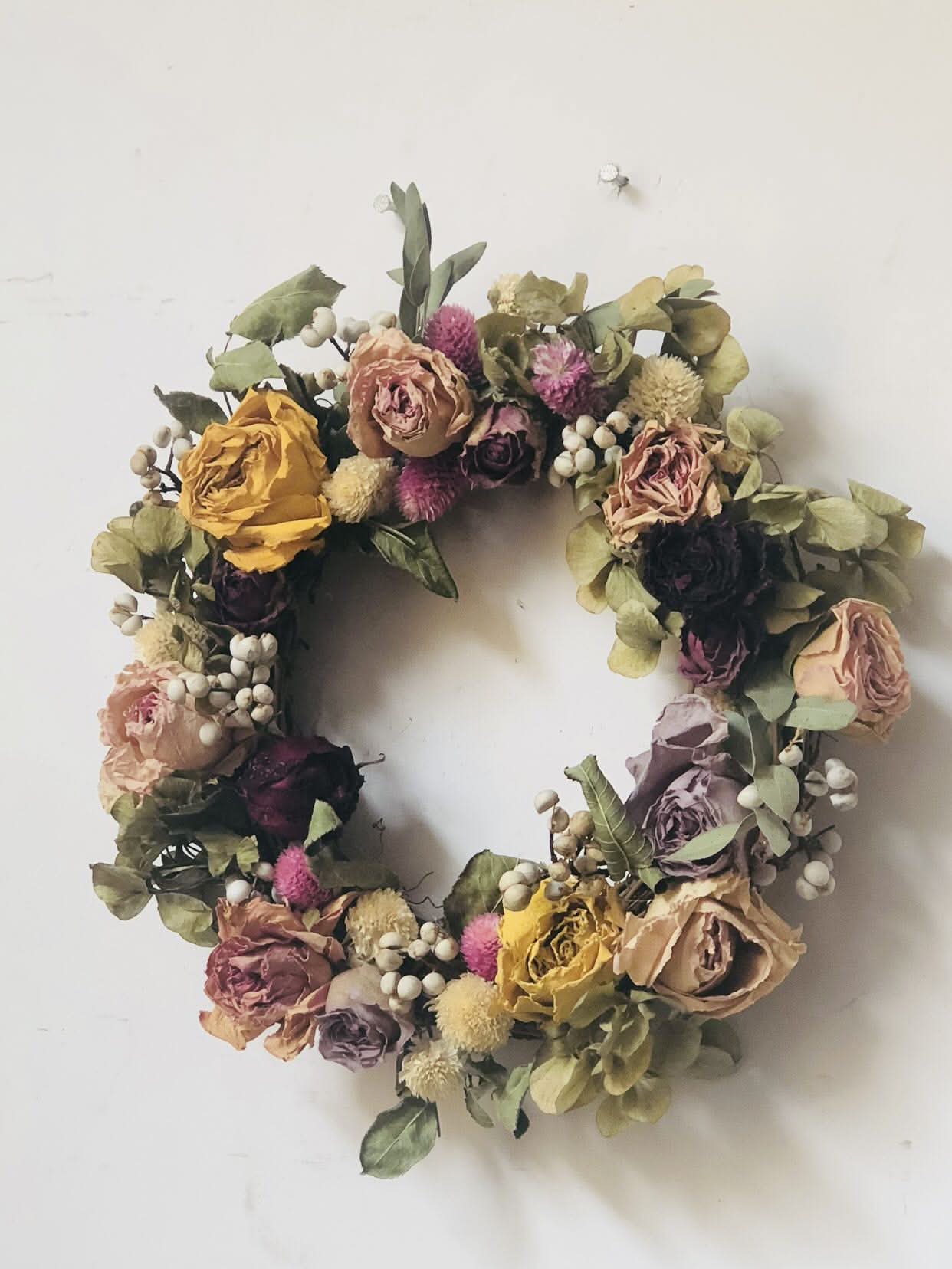 Natural Rose Round Garland: Dried roses, berries, and greenery on white wall